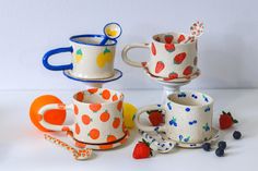 three cups and two saucers with fruit designs on them sitting next to each other