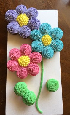 three flowers made out of fondant sitting on top of a piece of paper