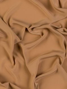 a close up view of a tan colored fabric with very soft folds and wrinkles