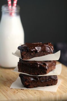 three chocolate brownies stacked on top of each other next to a glass of milk