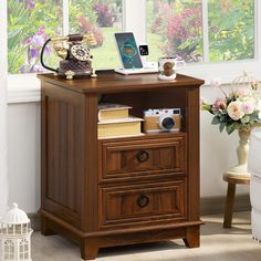 a wooden desk with two drawers and a laptop on top, in front of a window