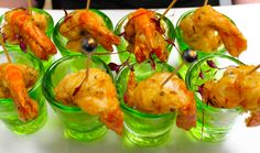 there are many shrimp skewers in small glass cups on the table with toothpicks sticking out of them