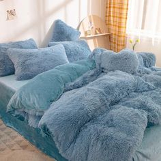 a bed covered in blue fluffy blankets and pillows