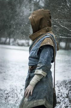 a man dressed in medieval clothing walking through the snow