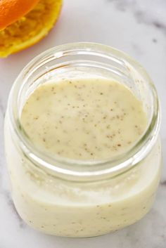 a glass jar filled with dressing next to an orange