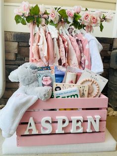 a wooden crate filled with lots of baby items next to flowers and stuffed animals on display