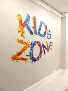 the kids zone sign is painted on the wall in an empty room with white walls