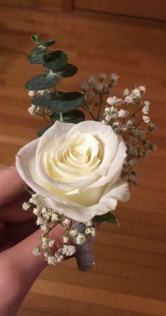 a hand holding a white rose and baby's breath