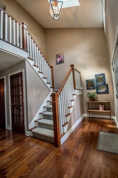 a staircase leading up to the second floor in a house with wood floors and white railings