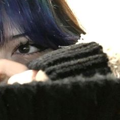 a close up of a person with blue hair wearing a black sweater and looking at the camera