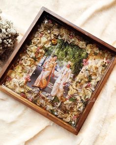 an image of two people standing next to each other in a wooden frame on a white blanket