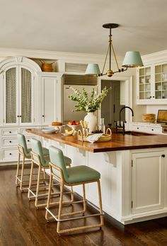 a kitchen with white cabinets and wooden counter tops next to a center island in the middle of an open floor plan