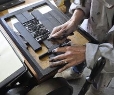 two people are working on some sort of art project with their hands and fingers resting on the table