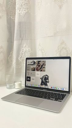 an open laptop computer sitting on top of a white desk next to a cup of coffee