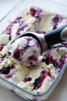 a scoop of ice cream in a glass dish with blueberries and raspberries