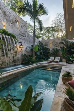 an outdoor swimming pool with waterfall in the middle and lounge chairs around it, surrounded by greenery