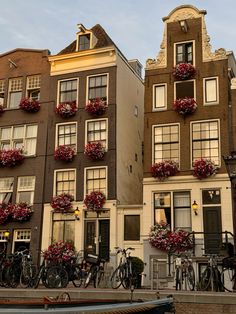 several bicycles parked in front of buildings with flower boxes on the balconies above them