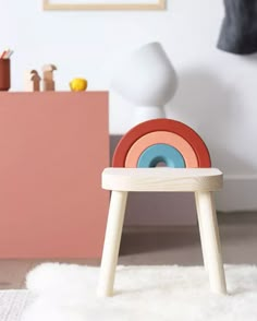 a small wooden stool with a rainbow colored wheel on it's seat in a child's room