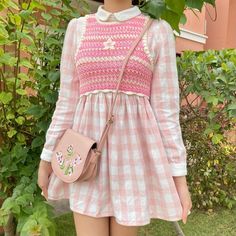 a woman wearing a pink and white dress holding a handbag in front of her face