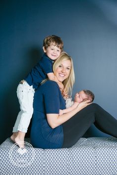 a woman sitting on top of a bed holding a child