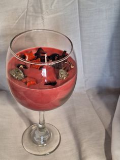 a wine glass filled with red liquid and garnishments