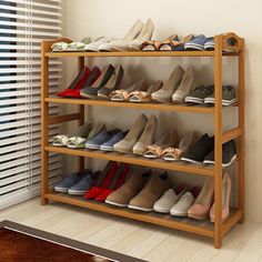 a wooden shoe rack filled with lots of shoes next to a window covered in blinds