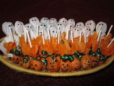 there are many pumpkins on the plate with candy sticks in them and ghost candies