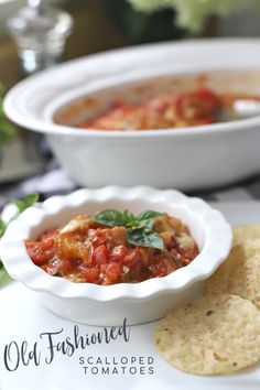 a white bowl filled with salsa next to tortilla chips on a plate in front of it