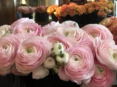 a bunch of pink and white flowers sitting on top of a black vase filled with water