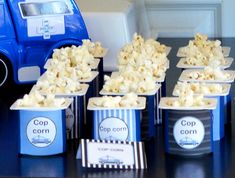 some popcorn cups are sitting on a table next to a blue toy car and other items