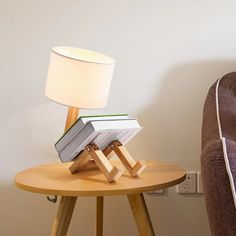 a lamp sitting on top of a wooden table next to a chair and a book