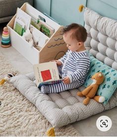 a baby sitting on the floor reading a book