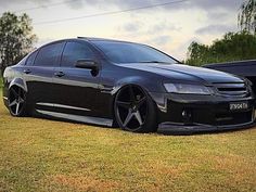 a black car parked on top of a lush green field