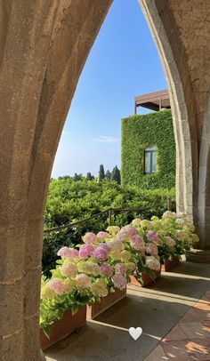 an archway leading to a building with flowers in the foreground