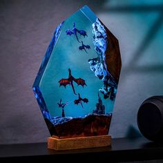 a blue glass trophy with red and black dragon silhouettes on the front, sitting on a wooden base