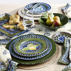 a table set with plates, napkins and fruit