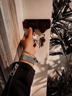 a person is holding keys in their hand while standing next to a wall mounted key rack