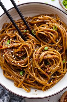 a white bowl filled with noodles and chopsticks