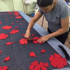 a woman is making red flowers out of felt