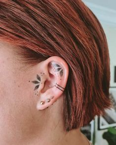 a woman with red hair has some piercings on her ear