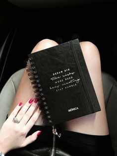 a woman sitting in a car holding a black book