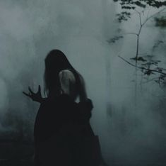 a woman standing in the fog with her hands out