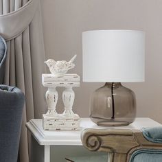 a lamp sitting on top of a white table next to a blue chair and ottoman