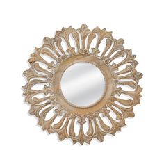 a mirror that is sitting on top of a white wall with an intricate design in the middle