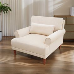 a white chair sitting on top of a hard wood floor next to a potted plant