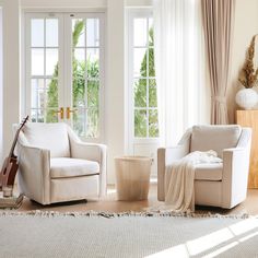 a living room with two chairs and a guitar on the floor in front of large windows