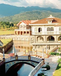 a bridge crossing over a river in front of a large house