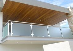 a balcony with glass railings and wood ceilinging on the side of a building