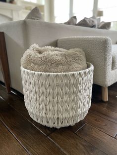 a large white basket sitting on top of a wooden floor next to a couch and chair