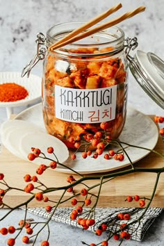 a glass jar filled with food sitting on top of a wooden cutting board next to some red berries